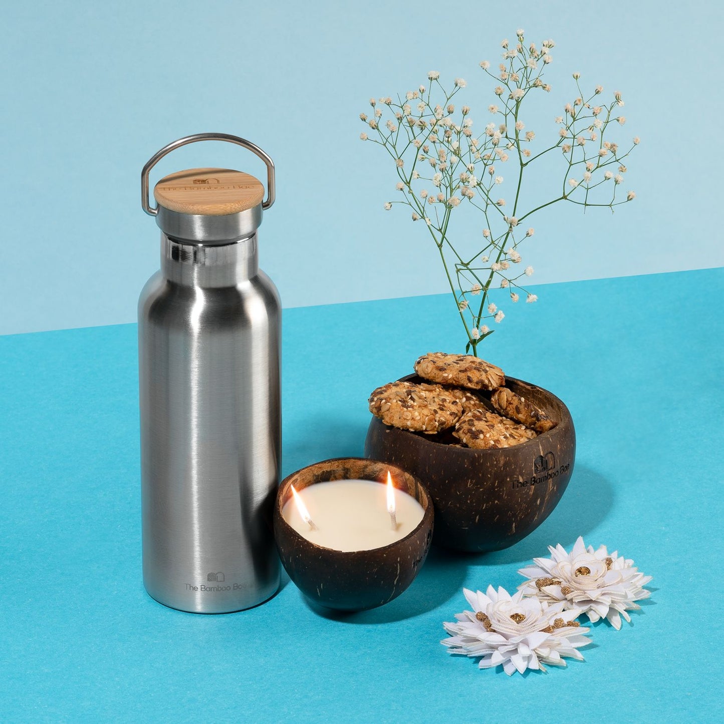 Eco-friendly gift set with stainless steel thermos bottle with bamboo lid, coconut soy candle, and coconut shell bowl – sustainable gifting option.