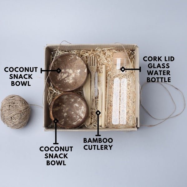 Sustainable gift hamper with coconut shell bowls, reusable bamboo cutlery set, and borosilicate glass bottle – eco-friendly dining and gifting option.